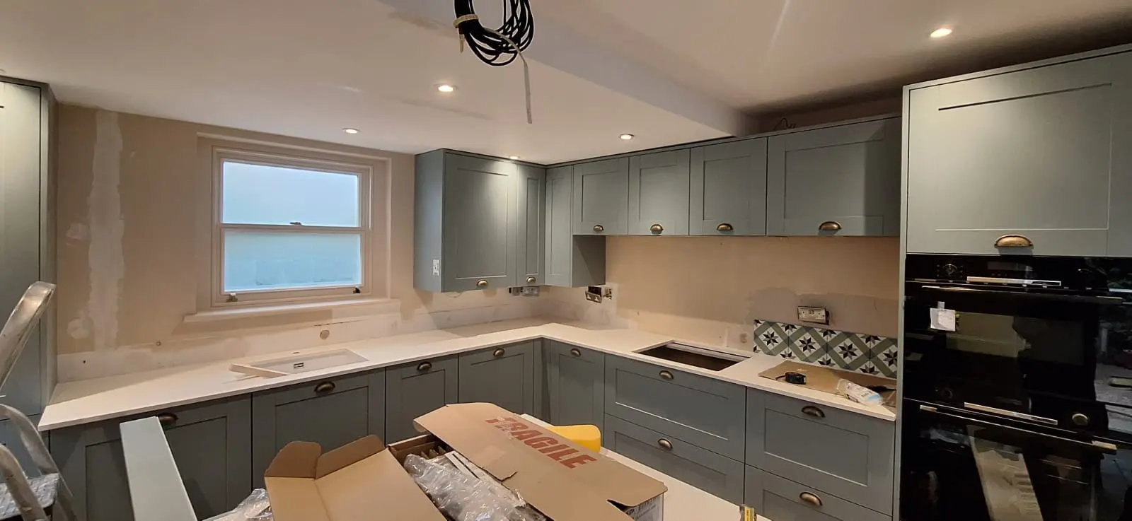 A finished sage green shaker kitchen with quartz worktops in Hampshire