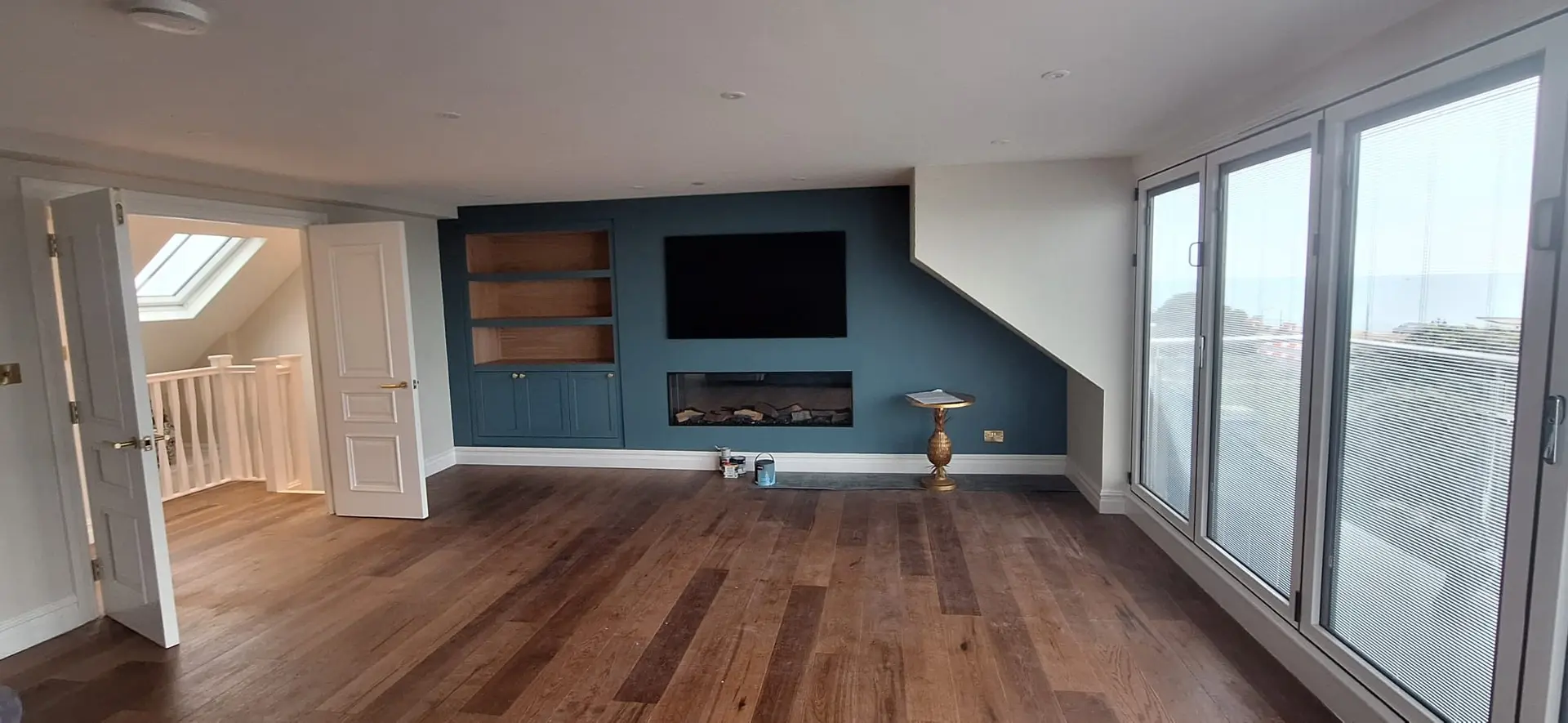 A finished loft living room with a bespoke media wall and sea view